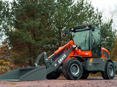 En röd Lastmaskin som står på ett fält